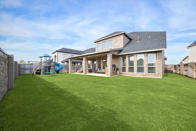 back of property with a lawn, a patio area, and a playground