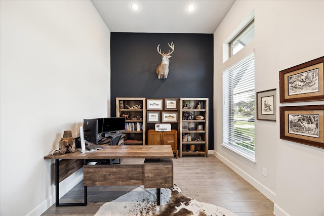 home office with plenty of natural light and light hardwood / wood-style flooring