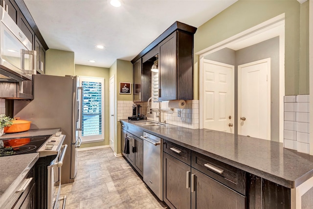 kitchen featuring decorative backsplash, appliances with stainless steel finishes, dark stone counters, dark brown cabinets, and sink