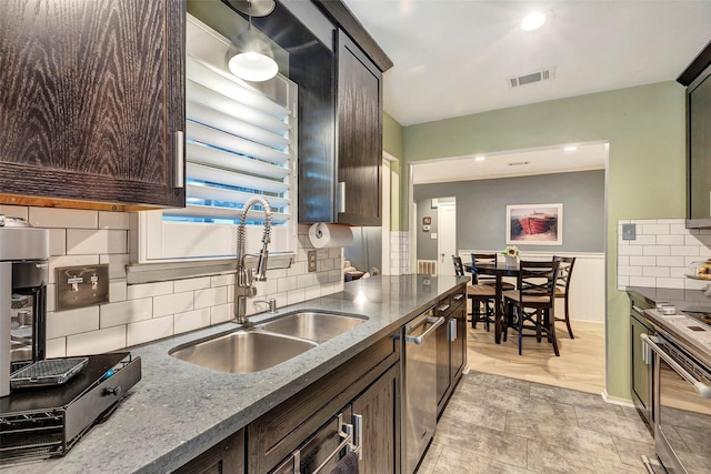 kitchen featuring dark brown cabinetry, decorative backsplash, sink, and appliances with stainless steel finishes