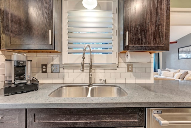 kitchen with dark brown cabinets, backsplash, stainless steel dishwasher, and sink