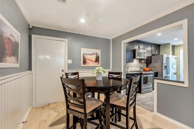 dining space with crown molding and light wood-type flooring