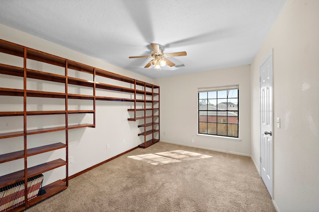 empty room featuring a textured ceiling, ceiling fan, and light carpet