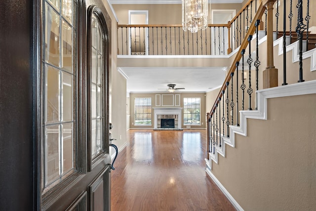 foyer featuring hardwood / wood-style floors, ceiling fan with notable chandelier, and ornamental molding