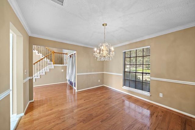 unfurnished room featuring hardwood / wood-style flooring, a notable chandelier, and crown molding