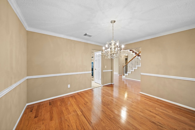 unfurnished room featuring hardwood / wood-style flooring, a notable chandelier, crown molding, and a textured ceiling