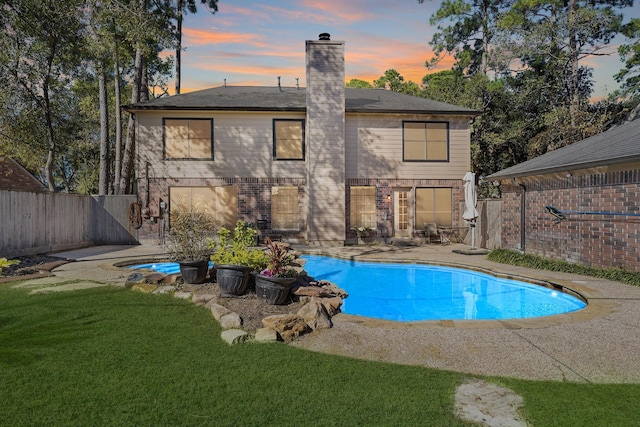 pool at dusk with a yard and a patio