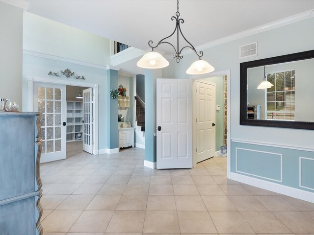 unfurnished dining area with french doors, light tile patterned floors, and crown molding