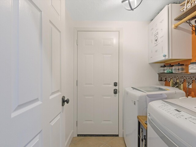 clothes washing area featuring cabinets, separate washer and dryer, and light tile patterned floors