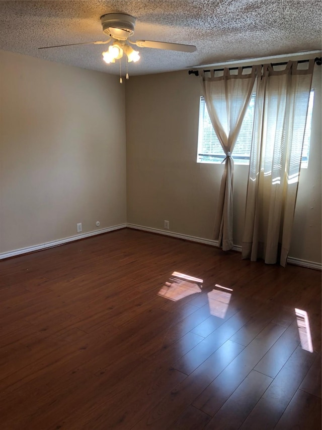 empty room with ceiling fan, dark hardwood / wood-style flooring, and a textured ceiling