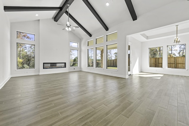 unfurnished living room featuring wood-type flooring, plenty of natural light, and beam ceiling