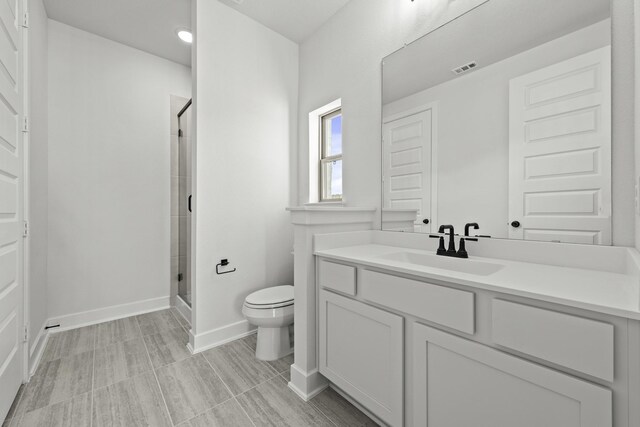 bathroom featuring vanity, toilet, and an enclosed shower