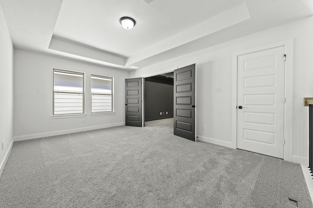 unfurnished bedroom with carpet floors and a raised ceiling