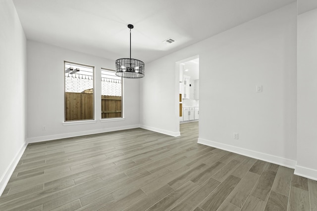 unfurnished dining area featuring hardwood / wood-style flooring and an inviting chandelier