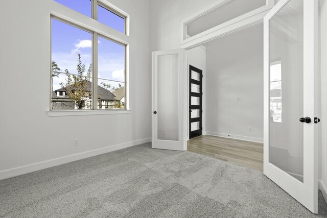 unfurnished room featuring french doors and light colored carpet