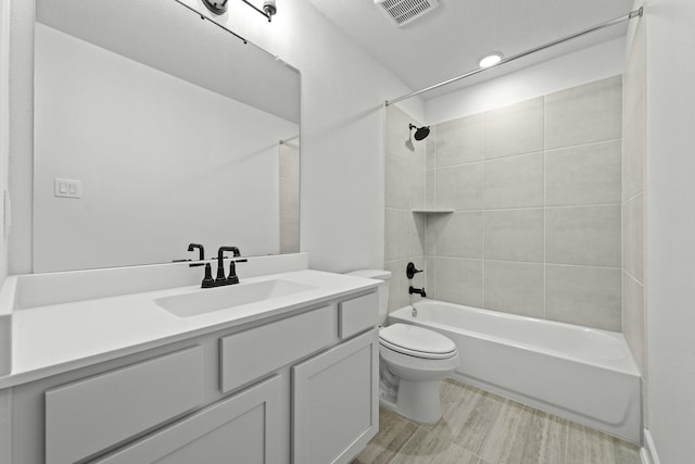 full bathroom with toilet, vanity, and tiled shower / bath