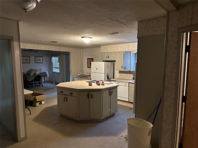 kitchen with ceiling fan, a kitchen island, white appliances, and a textured ceiling