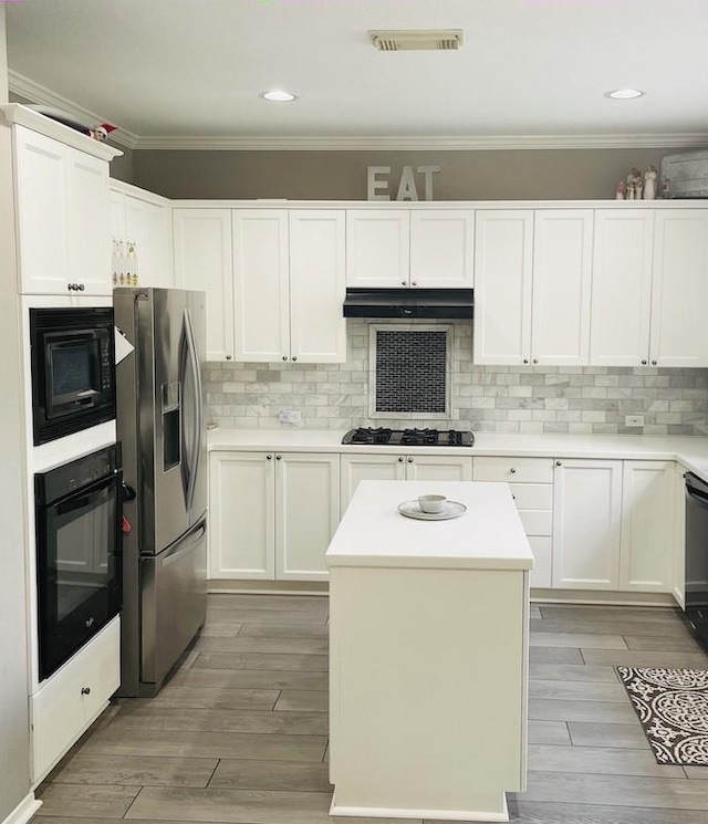 kitchen with white cabinetry, a center island, black appliances, and ornamental molding