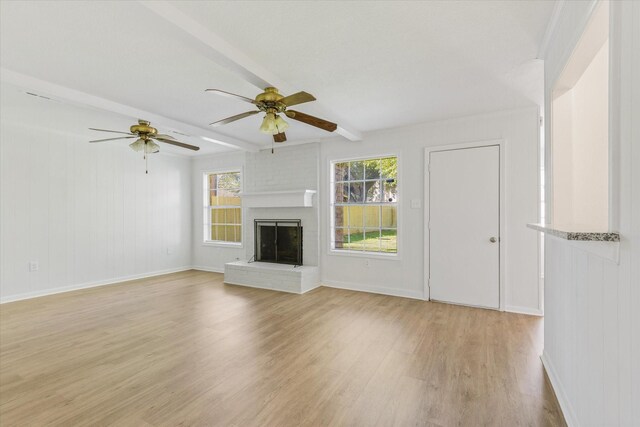 unfurnished living room with ceiling fan, beam ceiling, light wood-type flooring, and a brick fireplace