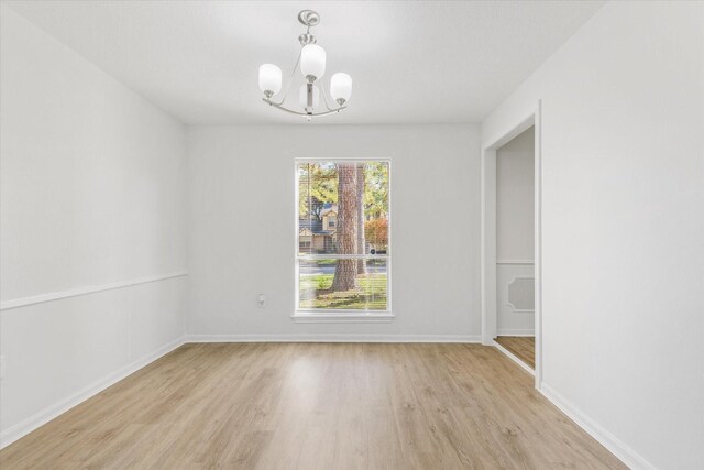 unfurnished room featuring light hardwood / wood-style flooring and a chandelier