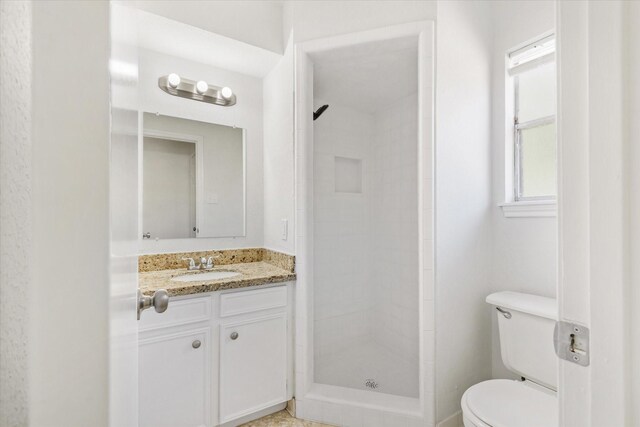 bathroom with a tile shower, vanity, and toilet