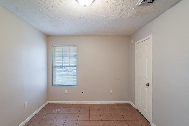 tiled spare room with a textured ceiling