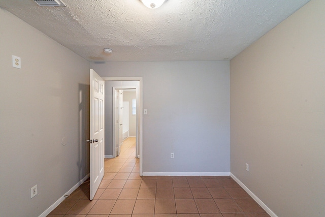 unfurnished room with light tile patterned floors and a textured ceiling