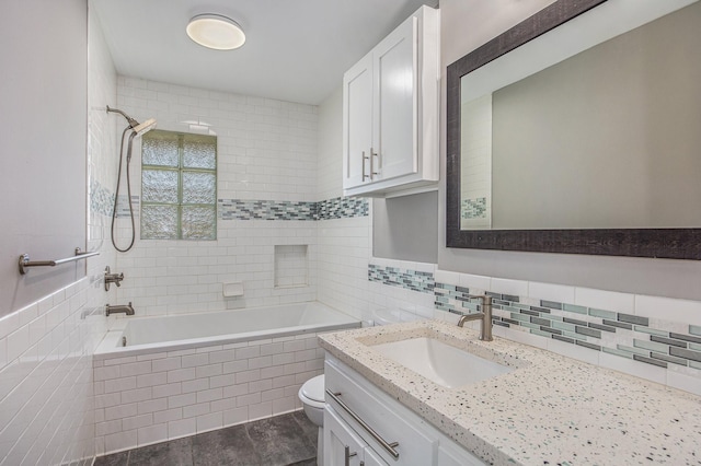 full bathroom with vanity, toilet, tiled shower / bath, and tile walls