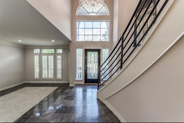 foyer featuring a towering ceiling, ornamental molding, and a notable chandelier