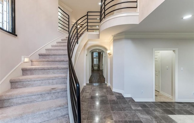 stairway with crown molding and a high ceiling