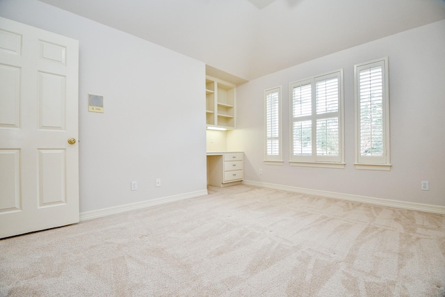 carpeted spare room with built in features and built in desk