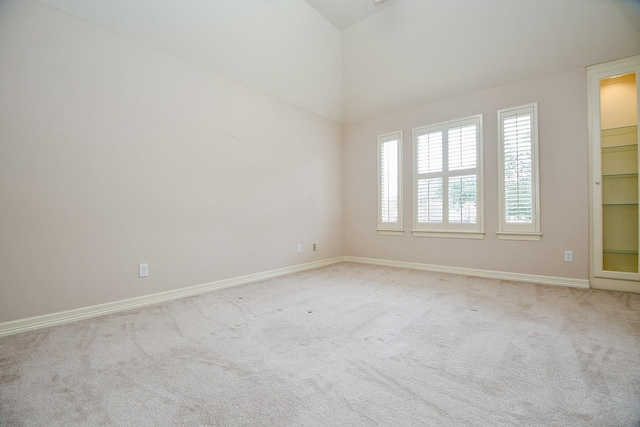 carpeted empty room featuring lofted ceiling