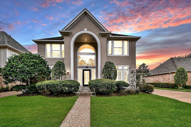 view of front of home with concrete driveway, a yard, and stucco siding