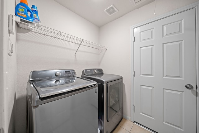 clothes washing area featuring light tile patterned flooring and washing machine and clothes dryer