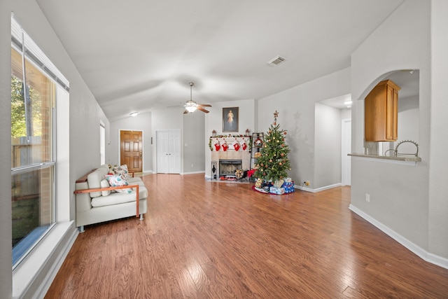 living room with a tiled fireplace, ceiling fan, hardwood / wood-style floors, and lofted ceiling