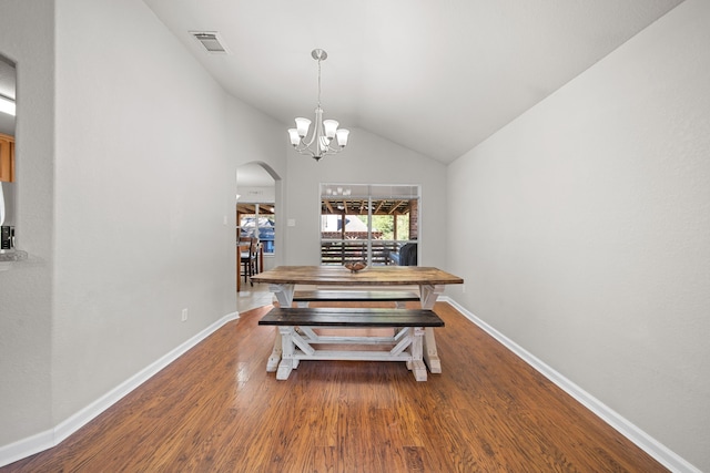 dining space with a chandelier, vaulted ceiling, and hardwood / wood-style flooring