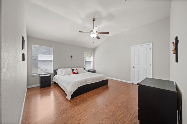 bedroom with hardwood / wood-style floors, vaulted ceiling, multiple windows, and ceiling fan