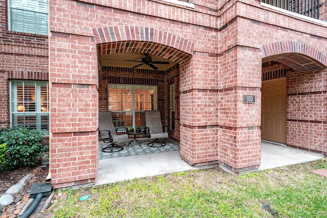 view of exterior entry featuring ceiling fan and a patio