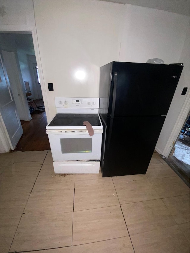 kitchen with black refrigerator and white electric range