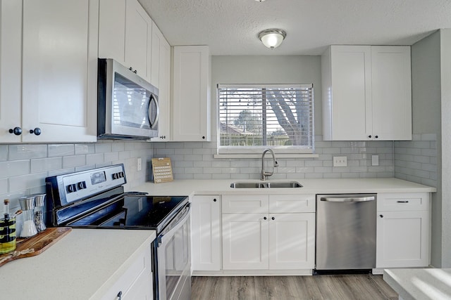 kitchen with white cabinets, backsplash, stainless steel appliances, and sink