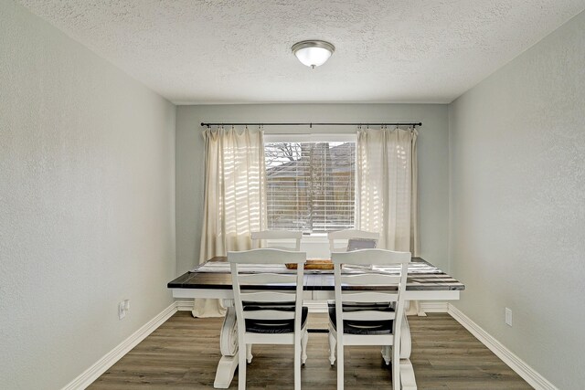 dining area with dark wood-type flooring and a textured ceiling