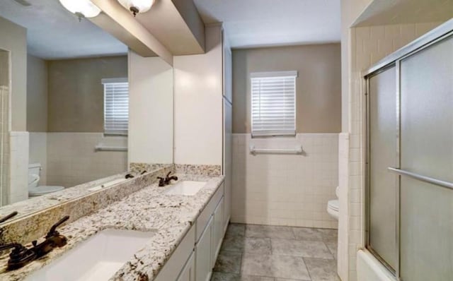 bathroom featuring vanity, toilet, and tile walls