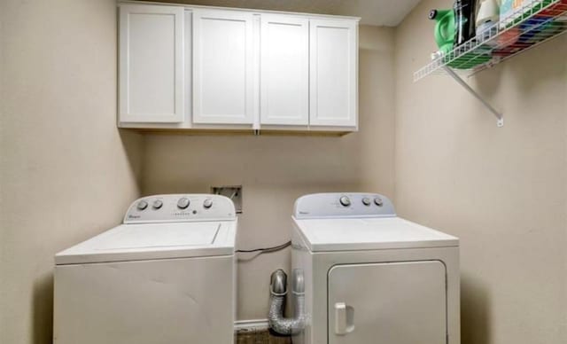 laundry area with separate washer and dryer and cabinets