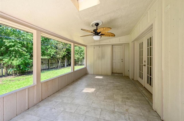 unfurnished sunroom with ceiling fan, a skylight, and french doors