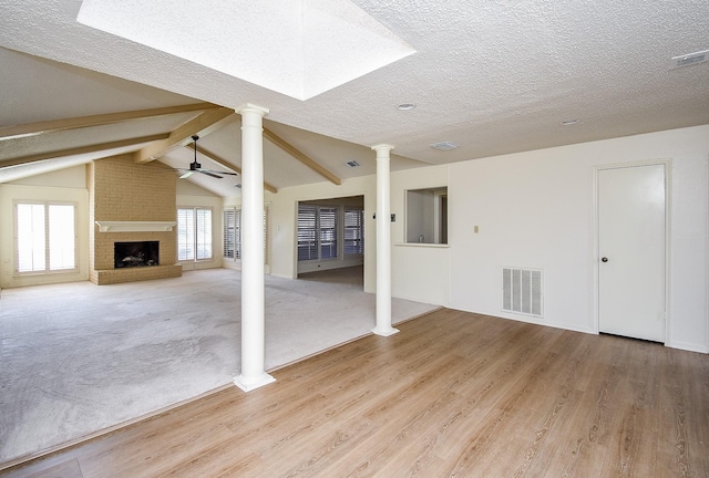 unfurnished living room featuring ceiling fan, lofted ceiling with beams, a textured ceiling, a fireplace, and hardwood / wood-style flooring