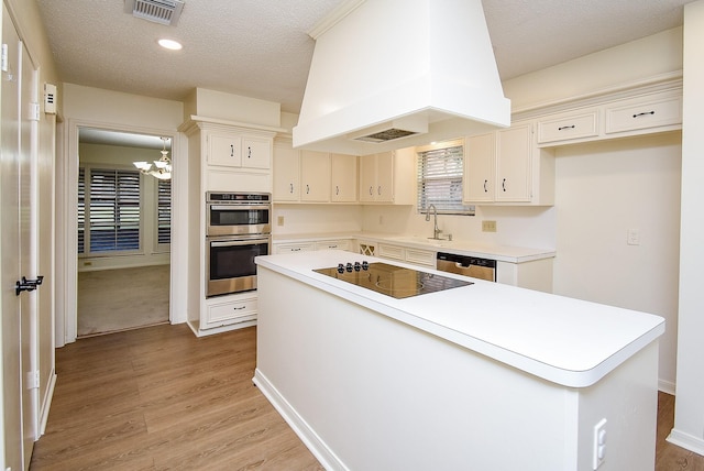 kitchen featuring a center island, light hardwood / wood-style flooring, a textured ceiling, custom exhaust hood, and appliances with stainless steel finishes