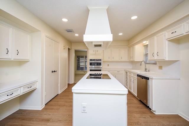 kitchen with a center island, light wood-type flooring, white cabinetry, and appliances with stainless steel finishes