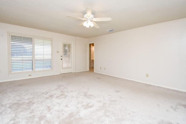 spare room featuring ceiling fan, light colored carpet, and a textured ceiling