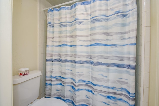 bathroom featuring a shower with curtain and toilet