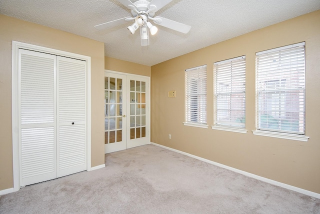 unfurnished bedroom with ceiling fan, french doors, a textured ceiling, light carpet, and a closet